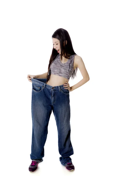 Шокированная женщина пробует свои старые джинсы на студии — стоковое фото