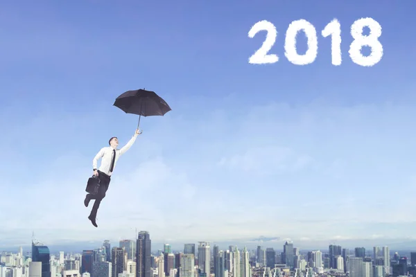 Male entrepreneur with umbrella and number 2018 — Stock Photo, Image