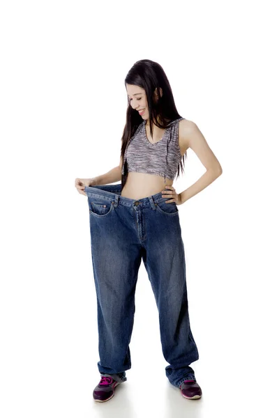 Glückliche Frau probiert ihre alten Jeans auf Studio — Stockfoto