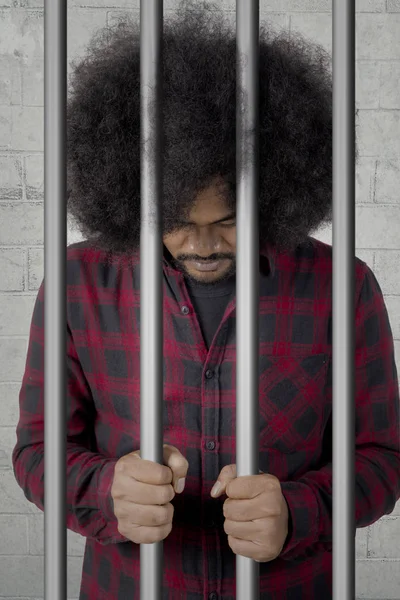 African prisoner standing behind bars — Stock Photo, Image