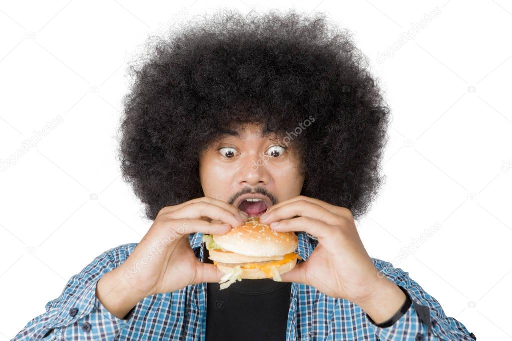 Afro man looks surprised with cheeseburger on studio