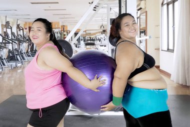 Bir fitness topu tutan iki şişman kadınlarla