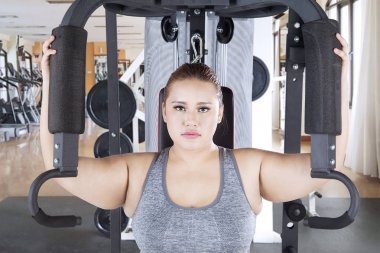 Şişman kadın onun pazı ağırlık makine ile egzersiz