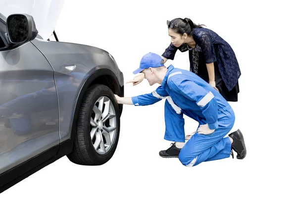 Kvinna med hennes mekaniker kontrollera en punktering — Stockfoto