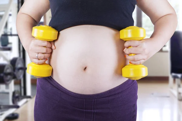 Pregnant woman holding two dumbbells — Stock Photo, Image
