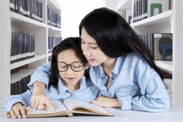 Mère et enfant avec livre à la bibliothèque — Photo