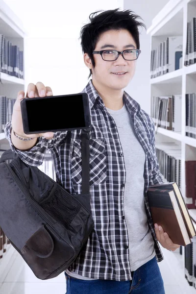 Mężczyzna student z smartphone w bibliotece — Zdjęcie stockowe