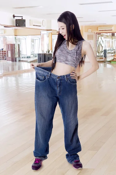 Gelukkig slanke vrouw probeert haar oude jeans — Stockfoto