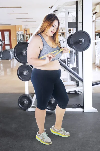 Счастливая толстая женщина измеряет грудь — стоковое фото