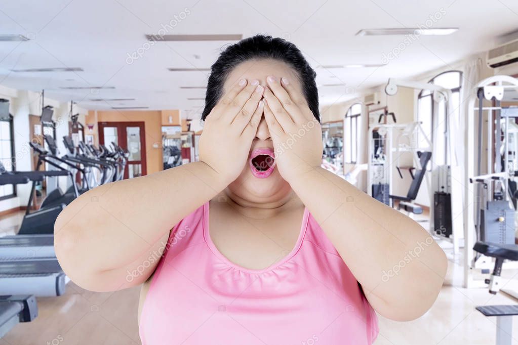 Overweight woman closing eyes in fitness center