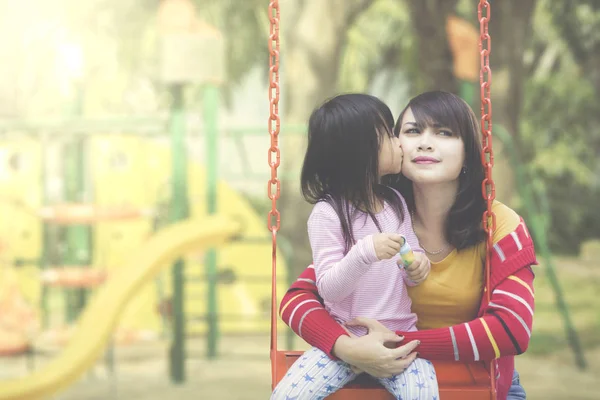 Filha beija mãe no parque infantil — Fotografia de Stock