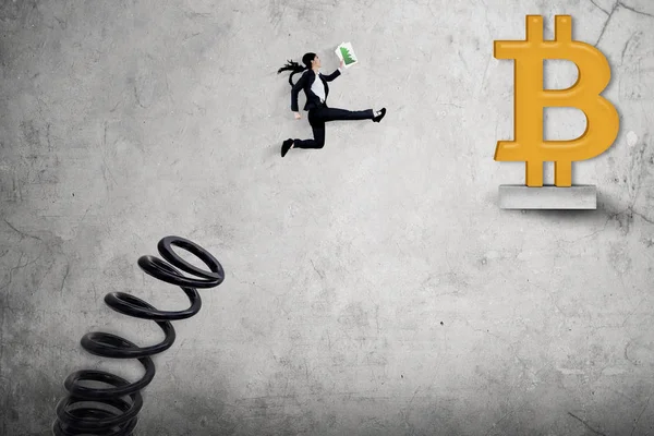 Junge Geschäftsfrau springt in Richtung Bitcoin-Symbol — Stockfoto