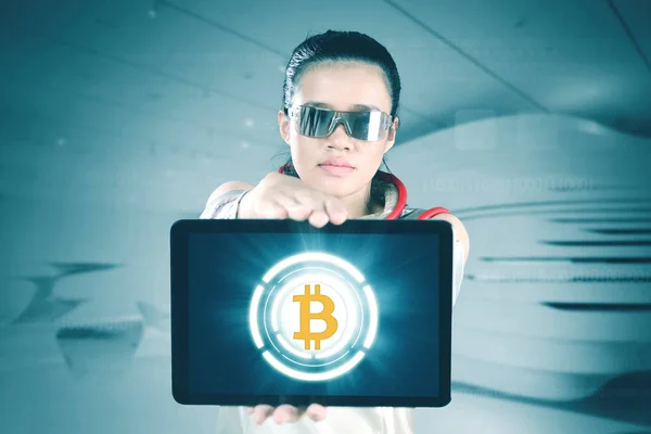 Futuristische Frau zeigt Bitcoin auf dem Tablet — Stockfoto