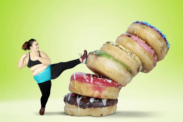 Overgewicht jonge vrouw schopt donuts — Stockfoto