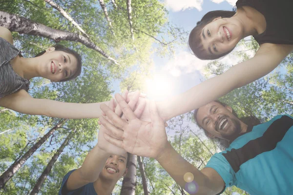 Four people joining their hands in the park — Stock Photo, Image