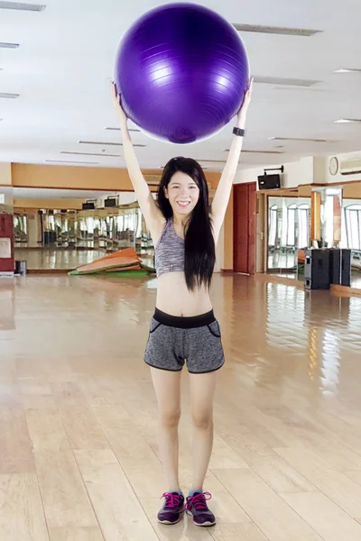Femme chinoise soulevant balle de remise en forme au centre de gym — Photo