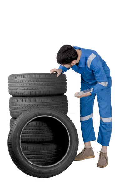 Male mechanic examining stack of tires — Stock Photo, Image