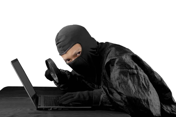 Hacker usando lupa en un ordenador portátil —  Fotos de Stock