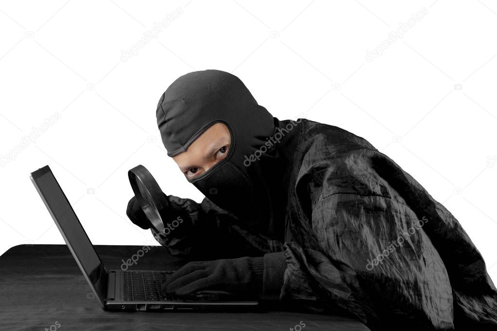 Hacker using magnifying glass on a laptop computer