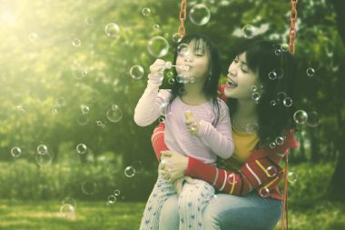 Anne ve kızı olan üfleme sabun köpüğü Park'ta eğlence