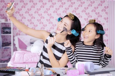 Genç Asyalı anne ve kızı ile saç curlers selfie yatak odasında alıyor