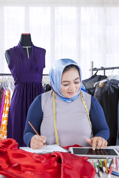 Självsäker kvinnliga muslimska mode designer arbetar med plagg — Stockfoto