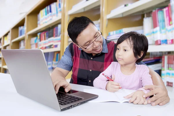 Asiatische Lehrer lehrt weibliche Schüler in Bibliothek — Stockfoto