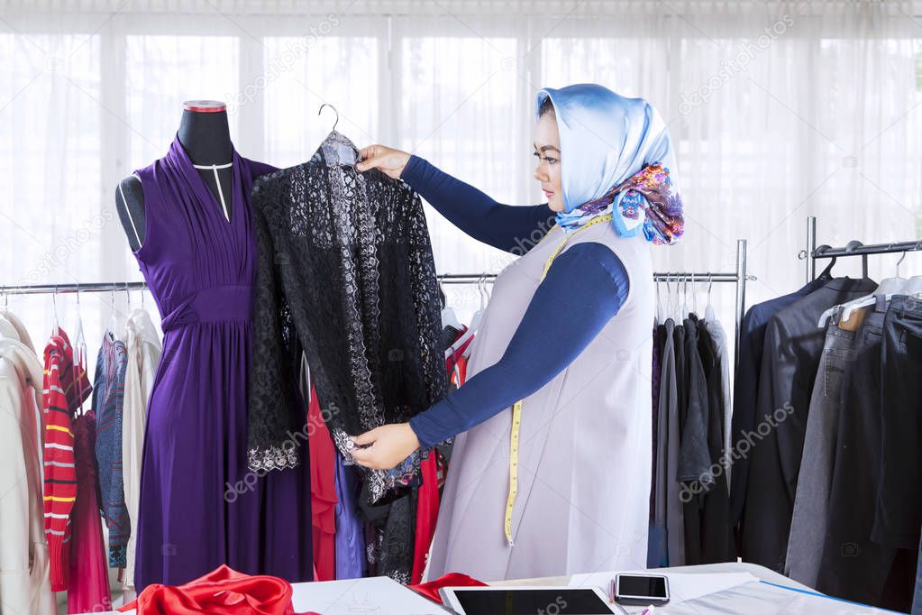 Confident female muslim fashion designer working with garments