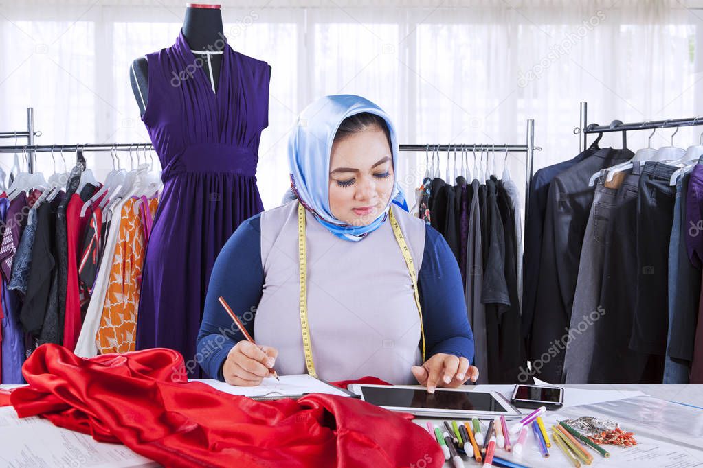 Female muslim fashion designer working with digital tablet