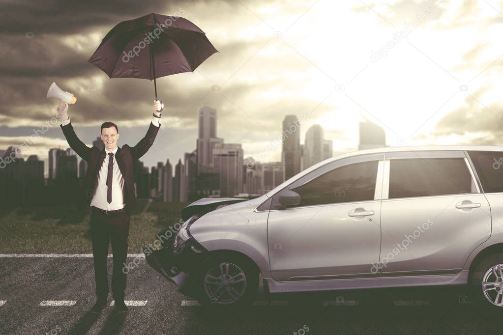 Happy businessman beside a crashed car