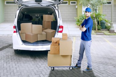 Karton kutular ile bir arabası yanında genç teslimat adam önünde Van durduğunu