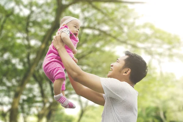 Padre lifting figlia con sfocatura albero sfondo — Foto Stock
