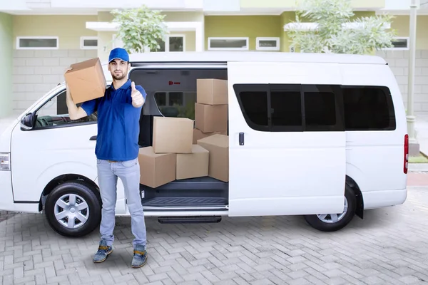 Młody dostawy człowiek z przodu Van z pudełka tekturowe Wyświetlono kciuk w — Zdjęcie stockowe