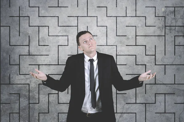 Confused businessman against complicated maze drawing background