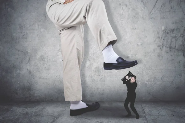 Terrifying businessman covering his face being attacked by a giant feet — Stock Photo, Image