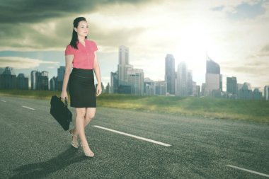 Parlak güneş ışığı ve ofis binaları arka plan ile yürüyüş başarılı iş kadını