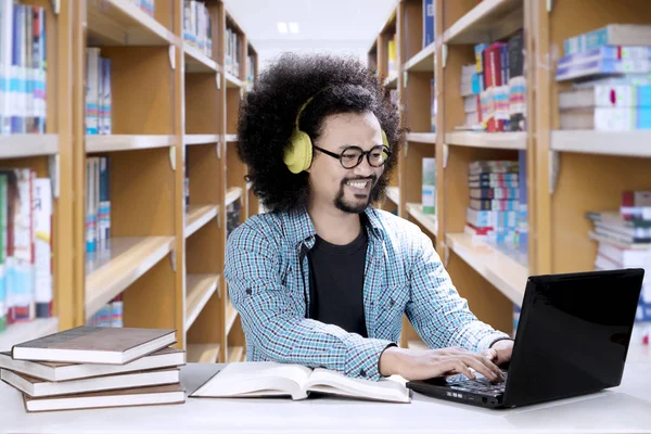 Manlig student höra musik i biblioteket — Stockfoto