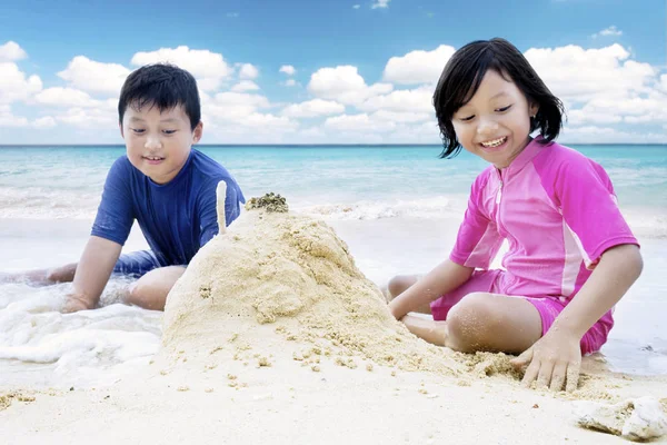 Menina brincando de areia com seu irmão — Fotografia de Stock