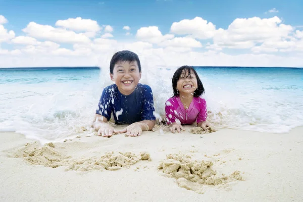 Malé děti si hrají vlny na pobřeží — Stock fotografie