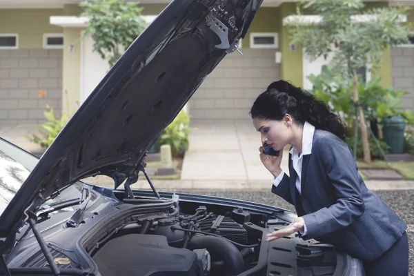 Upset Indian business woman talking on the phone asking for a mechanic help to fix broken down car — Stock Photo, Image