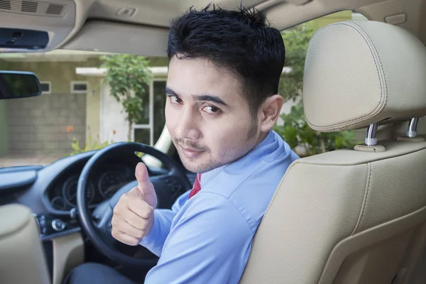 Man with in the driving seat. Looking back and showing thumb up — Stock Photo, Image