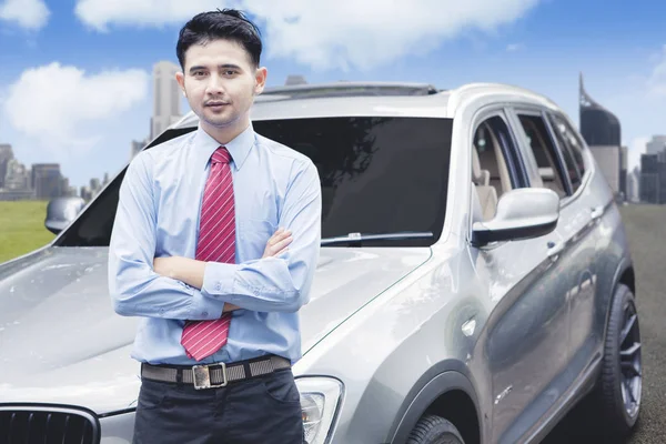 Успешный бизнесмен фотографируется перед роскошным автомобилем — стоковое фото