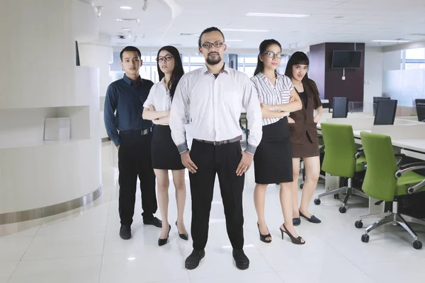 Уверенный в себе менеджер, стоящий со своей командой в офисе — стоковое фото
