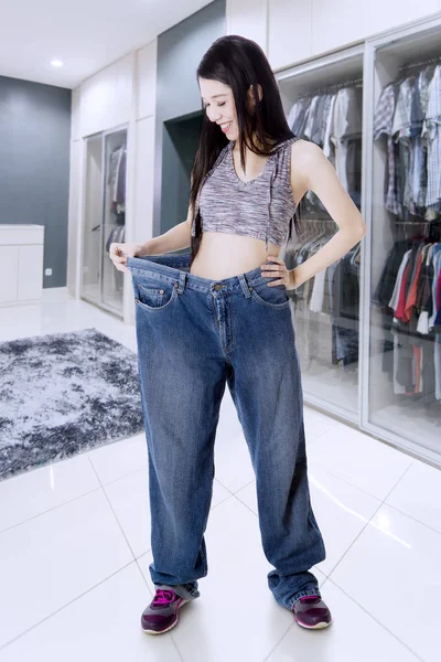 Chinese woman wearing her old jeans at home — Stock Photo, Image