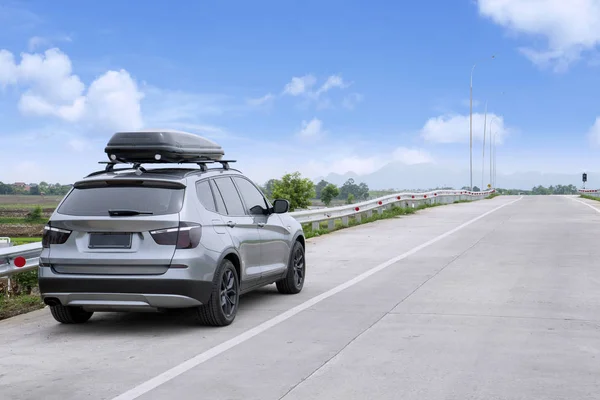 Podróży samochodów Suv z box dachowy na autostradzie przeciw błękitne niebo — Zdjęcie stockowe
