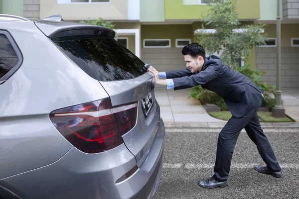 Asiático hombre de negocios empujando un roto abajo coche cerca de casa —  Fotos de Stock