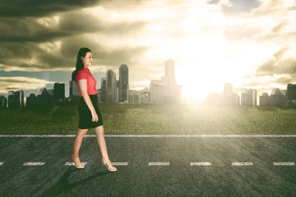 Succes zakenvrouw wandelen met fel zonlicht en kantoor gebouwen achtergrond — Stockfoto