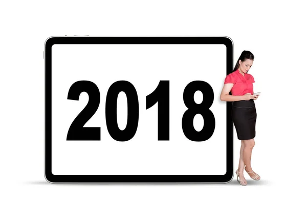 Donna d'affari con un tablet digitale appoggiato ai numeri del 2018 sul cartellone pubblicitario — Foto Stock