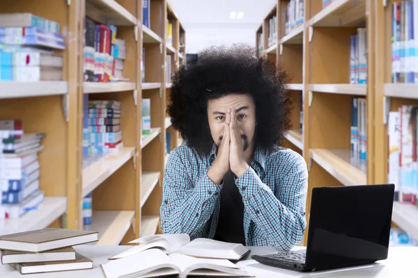 Αφρο άνδρας των φοιτητών που φαίνεται κουρασμένος στη βιβλιοθήκη — Φωτογραφία Αρχείου