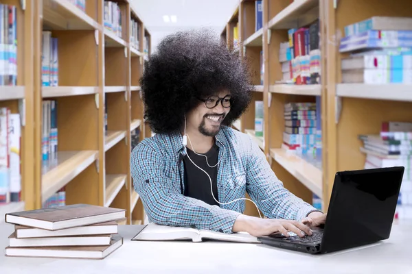 Afrikanska student använda hörlurar i biblioteket — Stockfoto